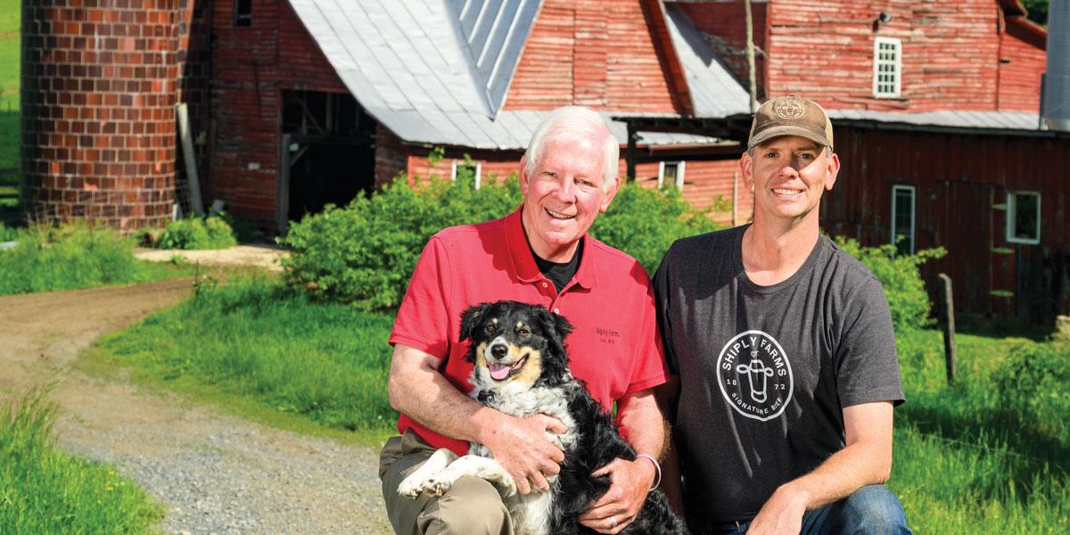 Bob and Gray Shipley with their dog Nellie in front of the historic red barn